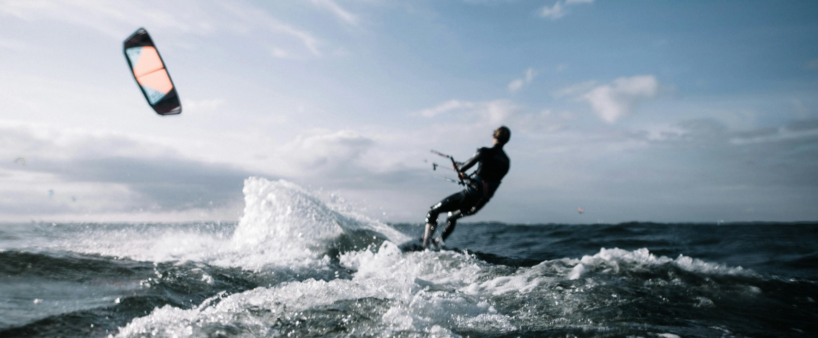 Kitesurfer using a waterproof intercom on the ocean in front of a blue sky