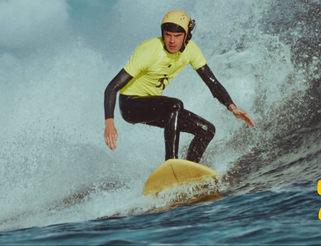 Ben Neumann using BbTalkin waterproof intercom while surfing on the water on a yellow surf board