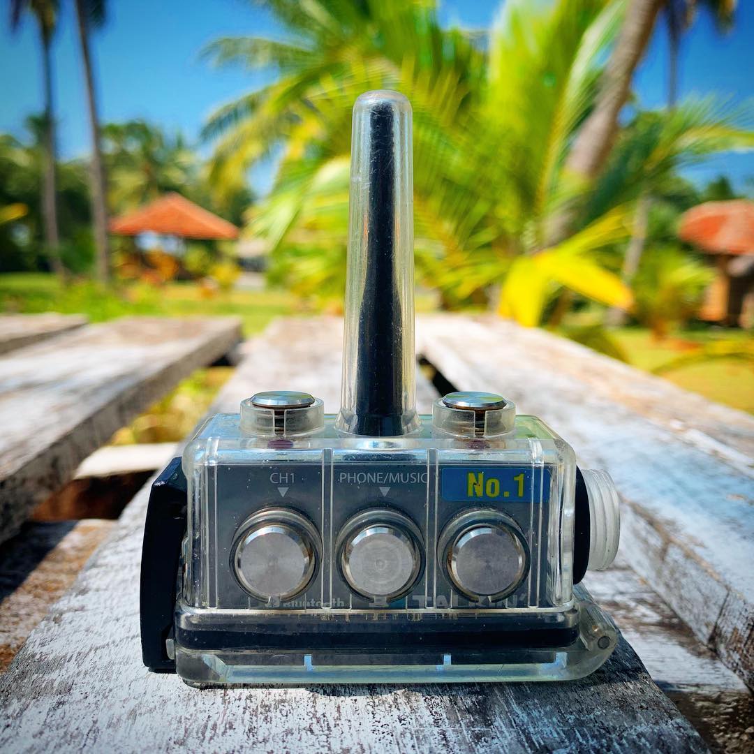 Vintage-style bbtalkin communication device on a wooden surface with a tropical background