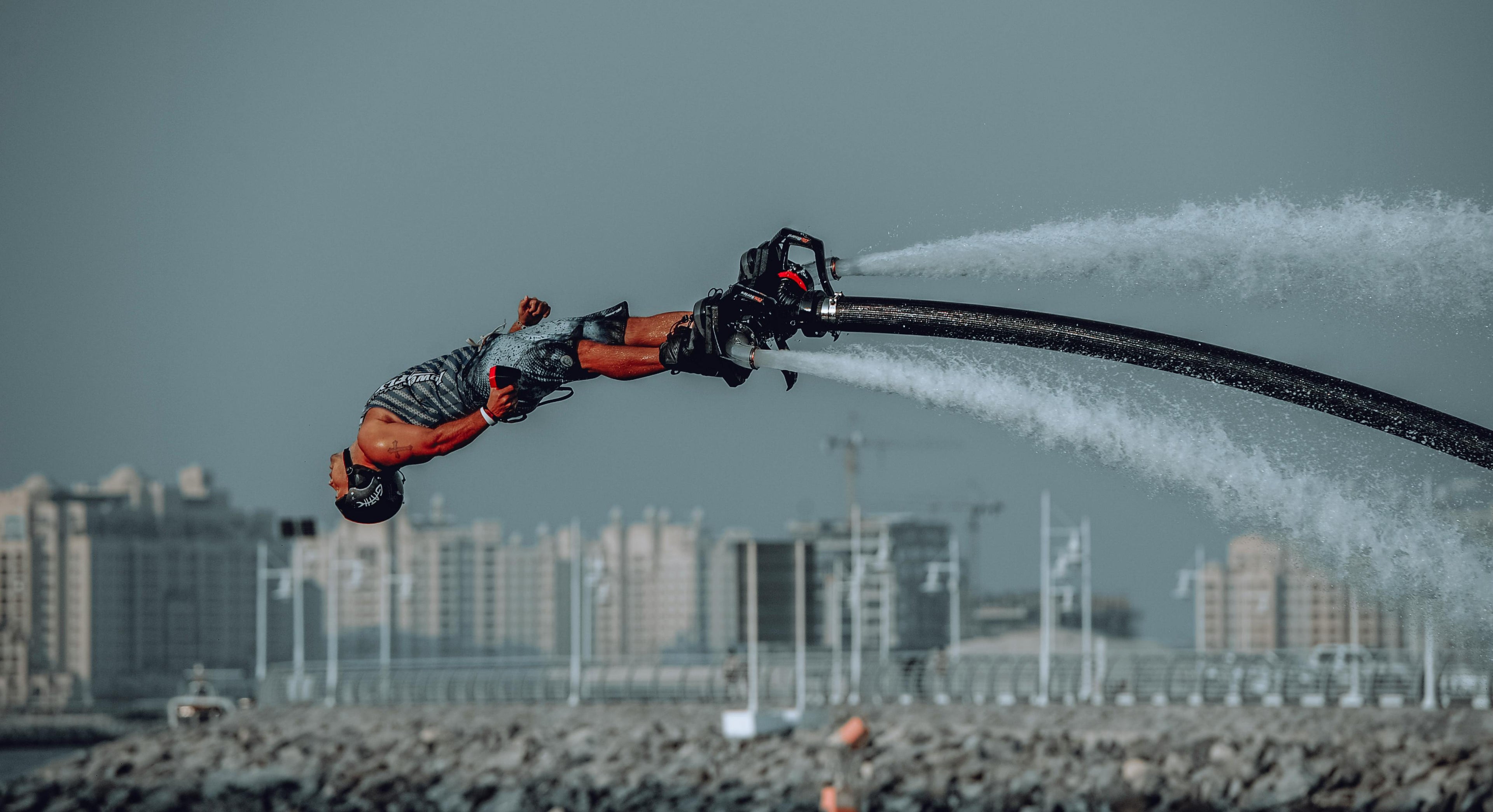 Flyboard rider performing a backflip over the water with strong jet streams, showing a typical environment for watersports communication systems.”