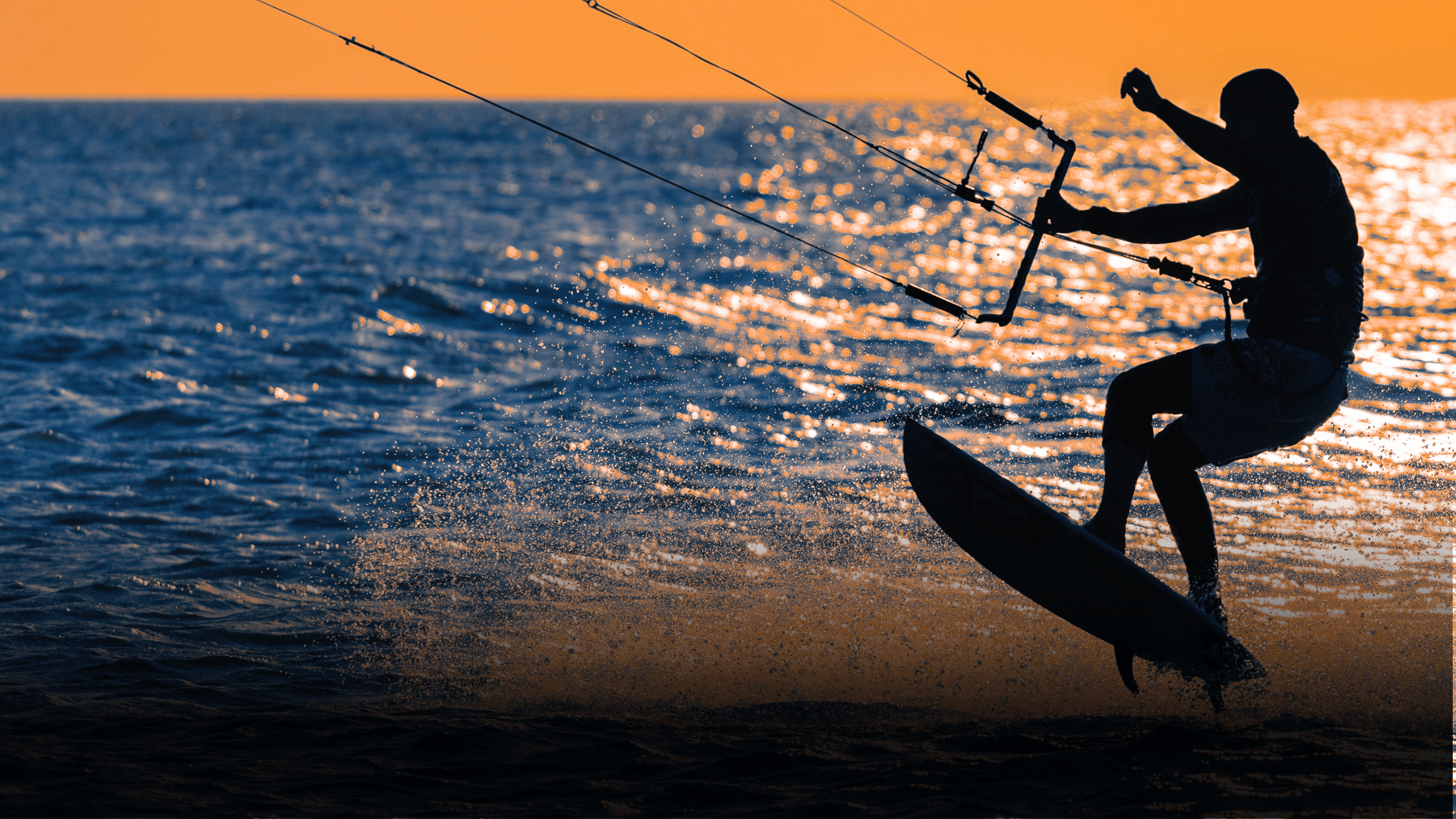 Person kite surfing on a body of water during sunset