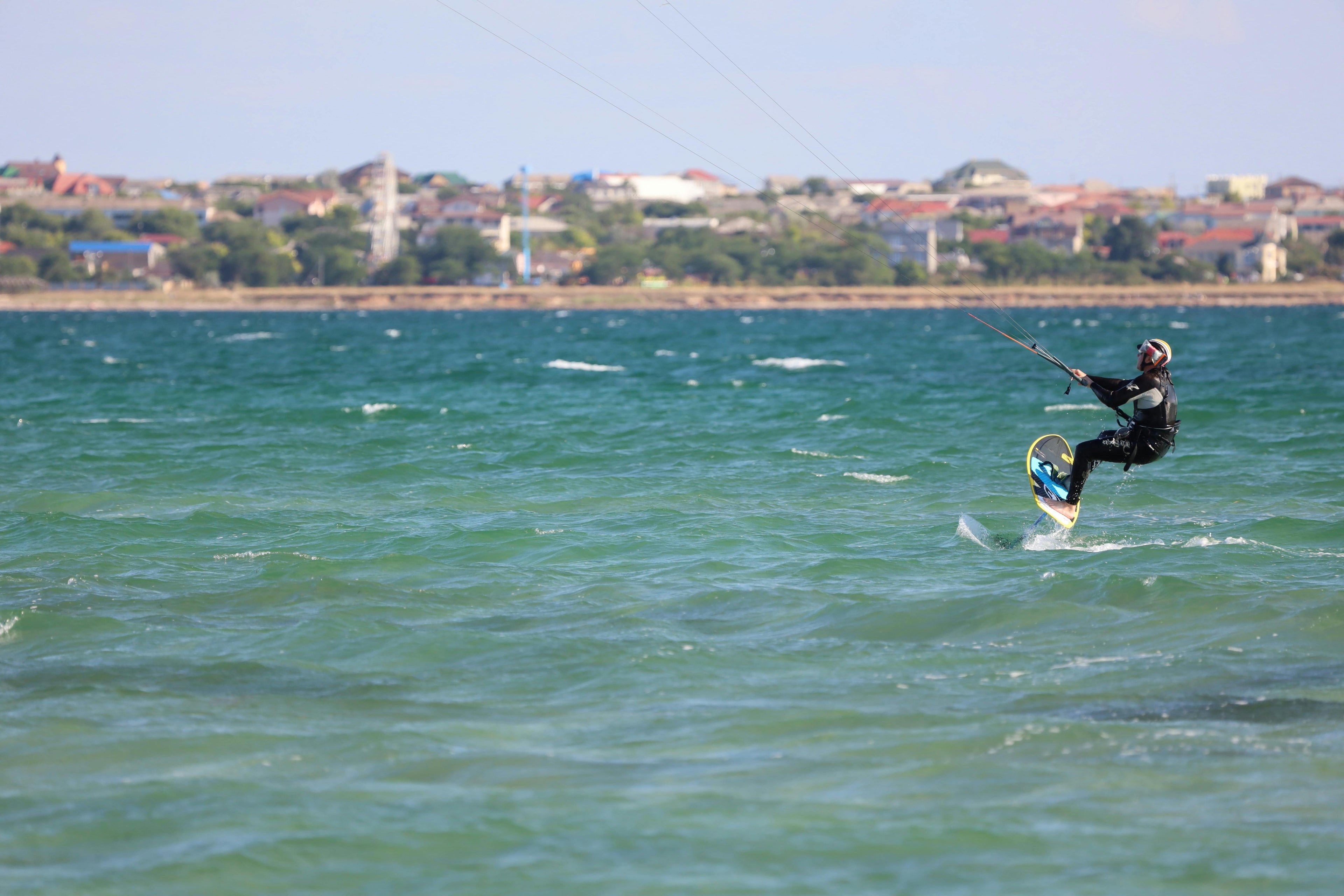 Person beim Kitesurfen auf einem Gewässer mit Stadtkulisse im Hintergrund
