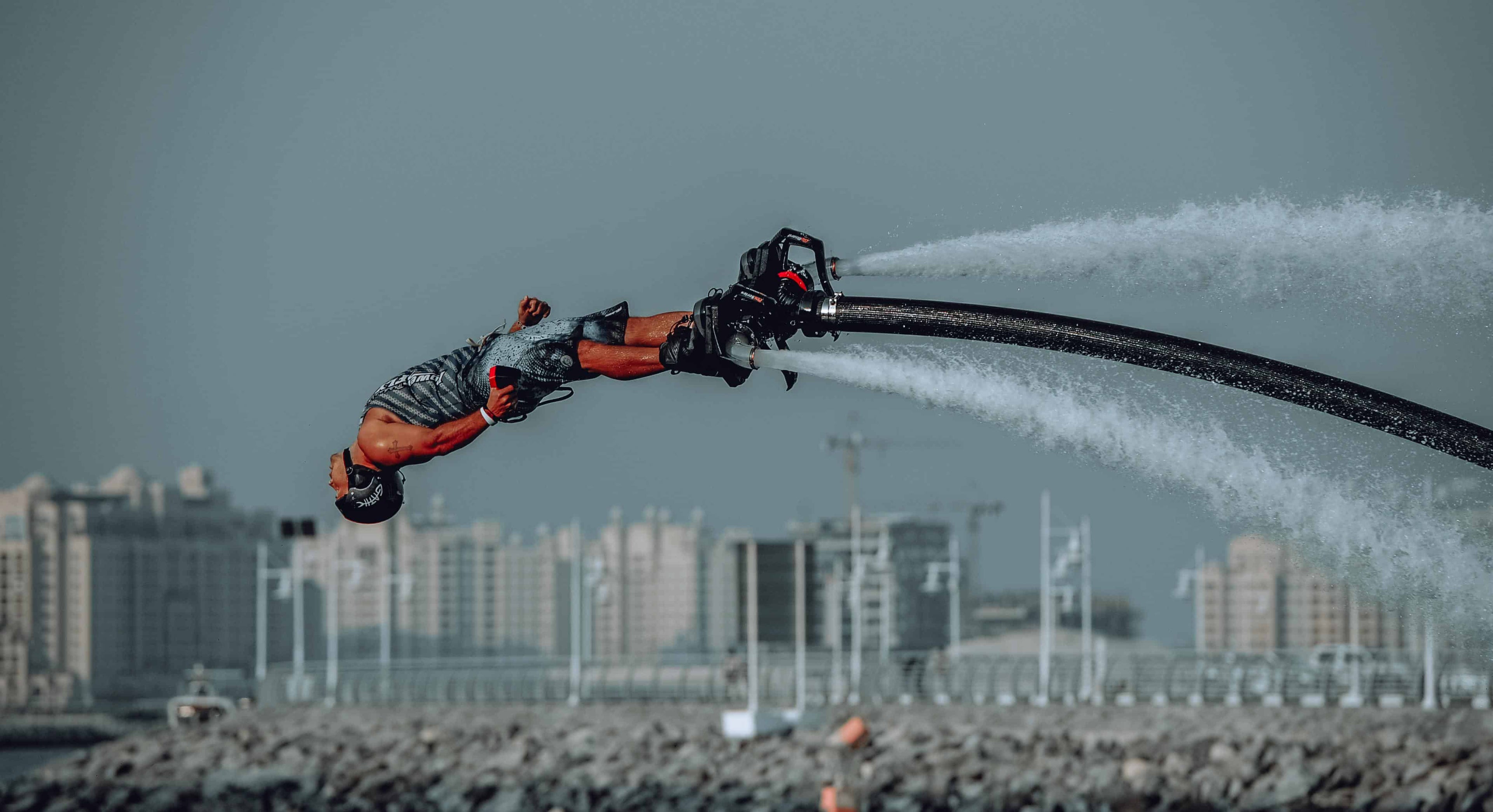 Un rider di flyboard esegue un salto mortale all'indietro sull'acqua con potenti getti d'acqua, mostrando un ambiente tipico per i sistemi di comunicazione per gli sport acquatici.