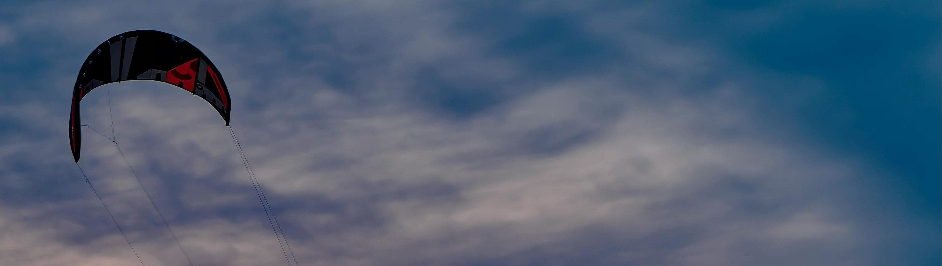 Aquilone da kitesurf che vola contro un cielo blu, mostrando l'ambiente tipico dei sistemi di comunicazione per gli sport acquatici.